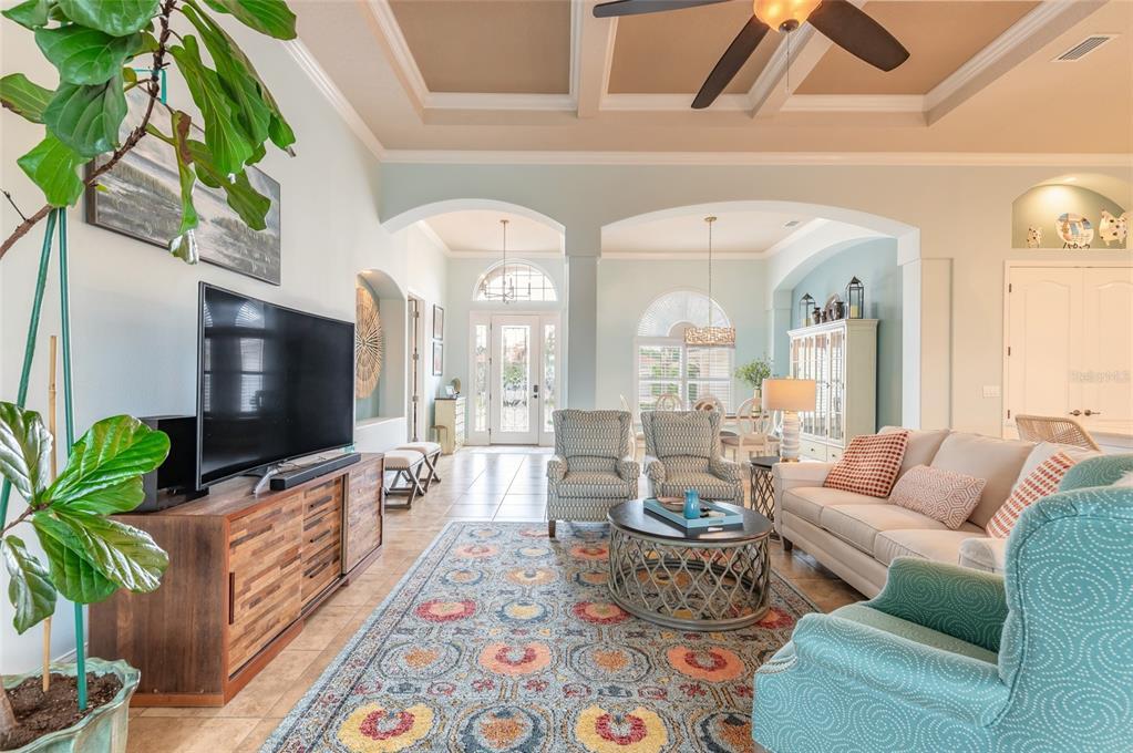 A living room with a coffered ceiling, patterned area rug, television console, and seating area — 2909 N ASCIANO COURT, NEW SMYRNA BEACH, FL