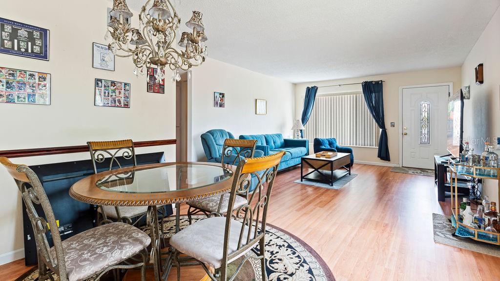 A living room and dining area with wood-look flooring, a glass table, and blue furniture — 2370 JAMAICAN STREET UNIT 30, CLEARWATER, FL