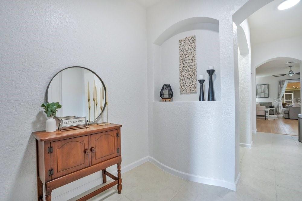 An entryway features a wooden console table, a round mirror, and an arched wall niche — 1259 FALLING STAR LANE, ORLANDO, FL