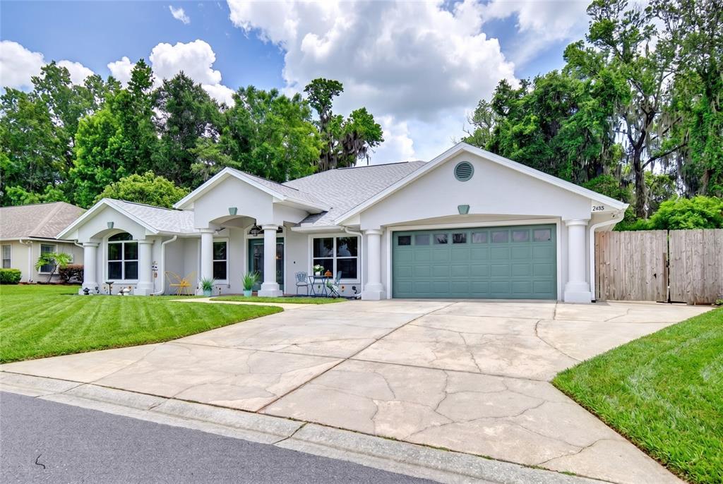 A single-story house with a green garage door, white columns, and a concrete driveway — 2408 SE 23RD PLACE, OCALA, FL