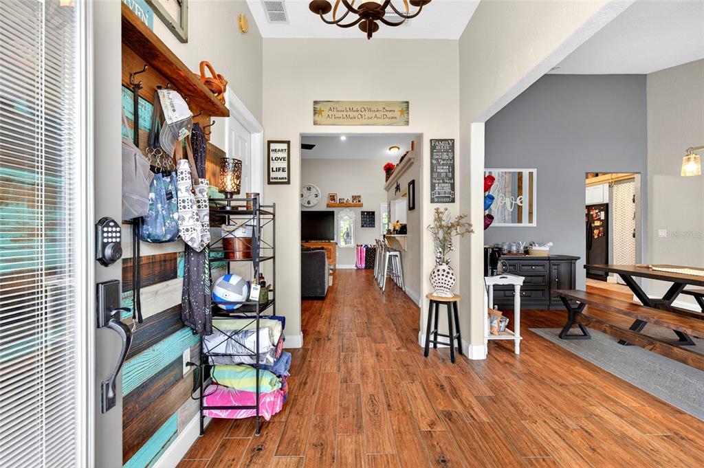 An entryway with wood-look flooring leads into a living area and dining room — 2408 SE 23RD PLACE, OCALA, FL