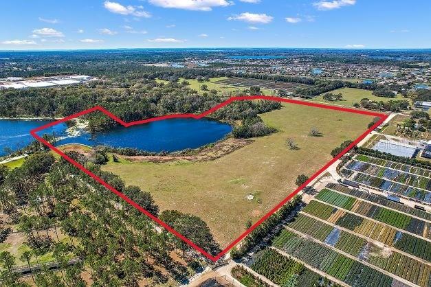 An aerial view shows a large, grassy plot of land bordering a lake and nursery — BRITT ROAD AND FUTURE FARM DRIVE, MOUNT DORA, FL