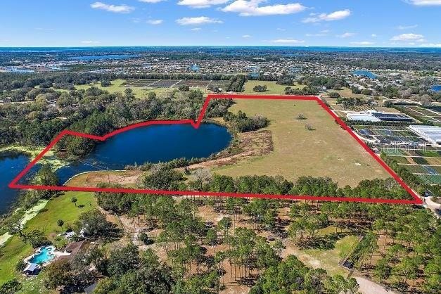 This aerial view shows a large, undeveloped plot of land featuring a private lake — BRITT ROAD AND FUTURE FARM DRIVE, MOUNT DORA, FL
