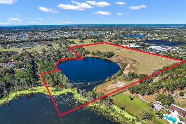 An aerial view shows a large parcel of land outlined in red featuring a central lake — BRITT ROAD AND FUTURE FARM DRIVE, MOUNT DORA, FL