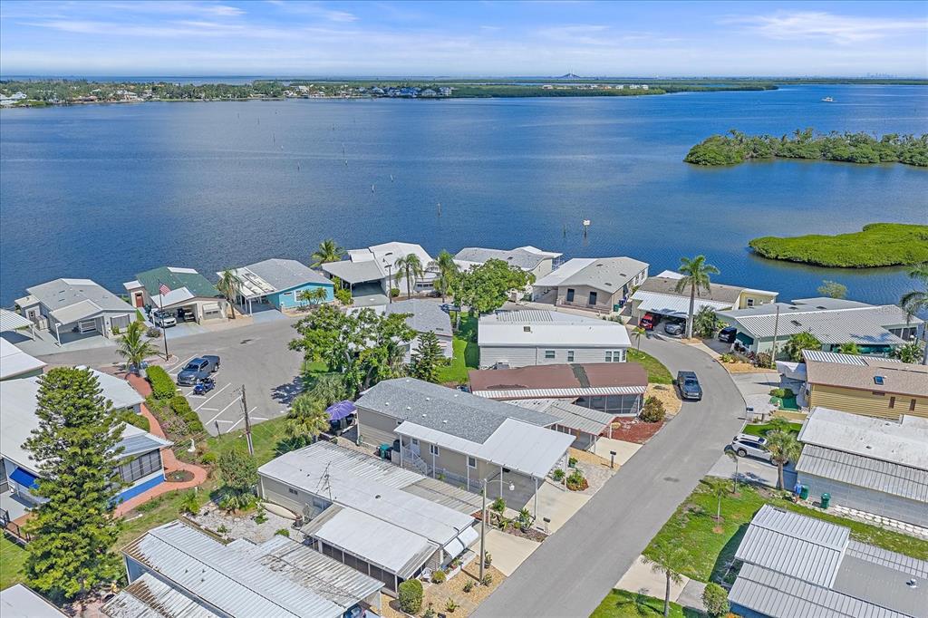 An aerial view shows a waterfront neighborhood of manufactured homes with carports and paved streets — 203 BIMINI DRIVE, PALMETTO, FL