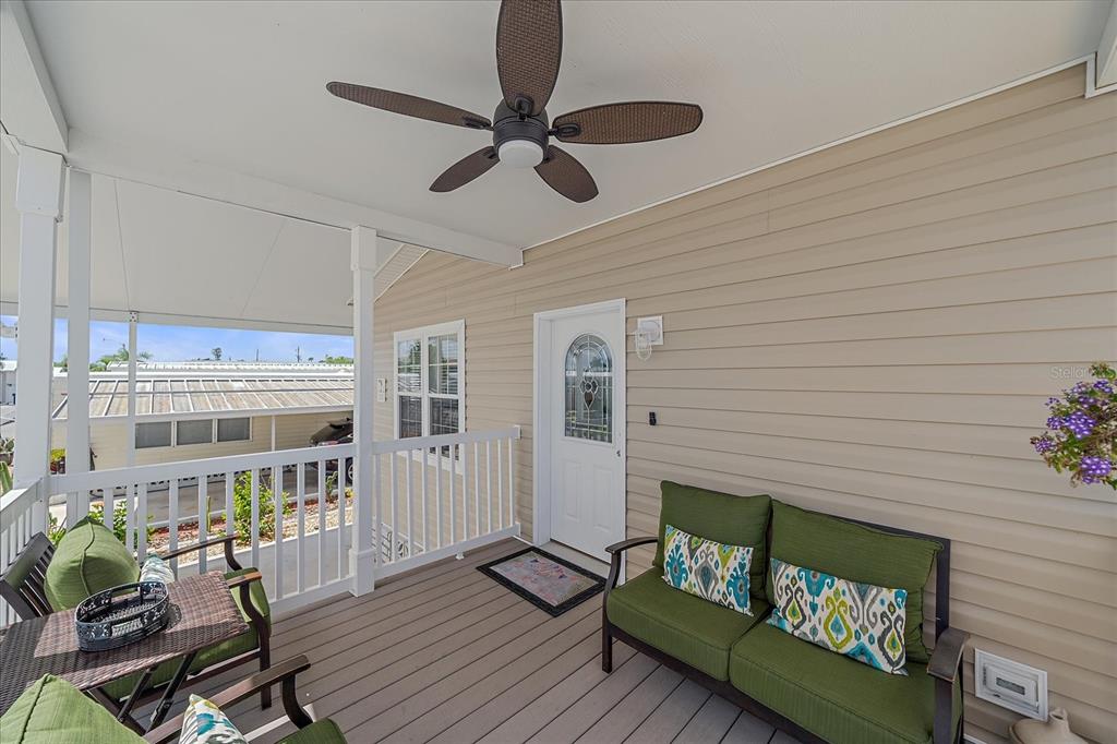 A covered porch features a ceiling fan, a green loveseat, and a white front door — 203 BIMINI DRIVE, PALMETTO, FL