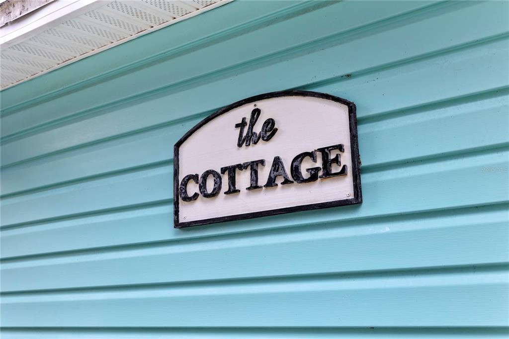 A sign reading "the COTTAGE" is mounted on light blue horizontal vinyl siding — 1209 QUINTUPLET COURT, CASSELBERRY, FL