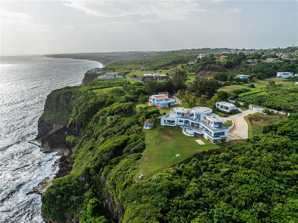 An aerial view shows a modern multi-level house situated on a cliff overlooking the ocean — 991 CALLE ESTACION, QUEBRADILLAS, PR