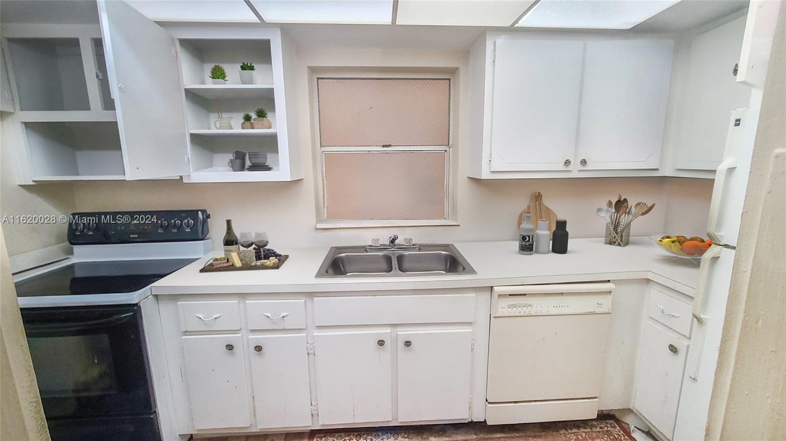 A kitchen features white cabinets, a double sink, a black stove, and a white dishwasher — 7410 SW 82nd St # K211, Miami FL 33143, MIAMI, FL