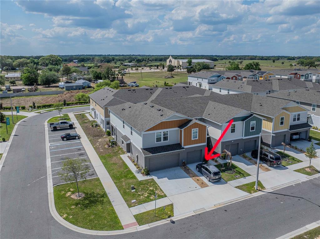 An aerial view shows a multi-unit townhouse complex with a red arrow pointing to a driveway — 4345 HILLOCK BOULEVARD, HAINES CITY, FL
