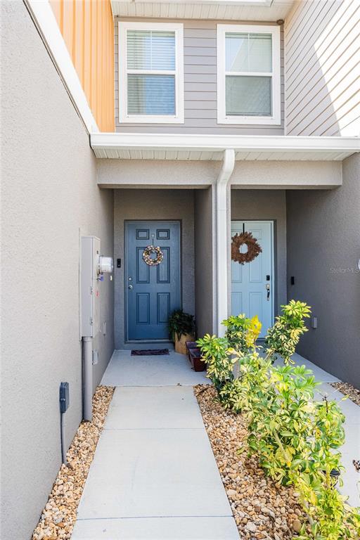 A concrete walkway leads to two front doors with wreaths under a shared covered porch — 4345 HILLOCK BOULEVARD, HAINES CITY, FL