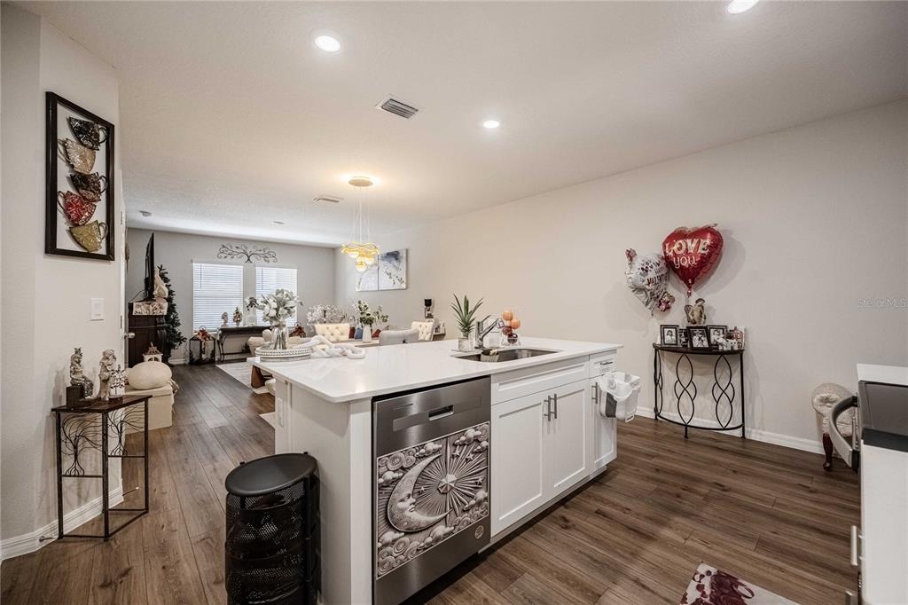 A kitchen island with a decorative dishwasher faces an open-concept living and dining area — 4345 HILLOCK BOULEVARD, HAINES CITY, FL