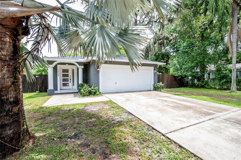 A single-story house with a gray exterior, a white garage door, and a pink front door — 1508 E JEAN STREET, TAMPA, FL