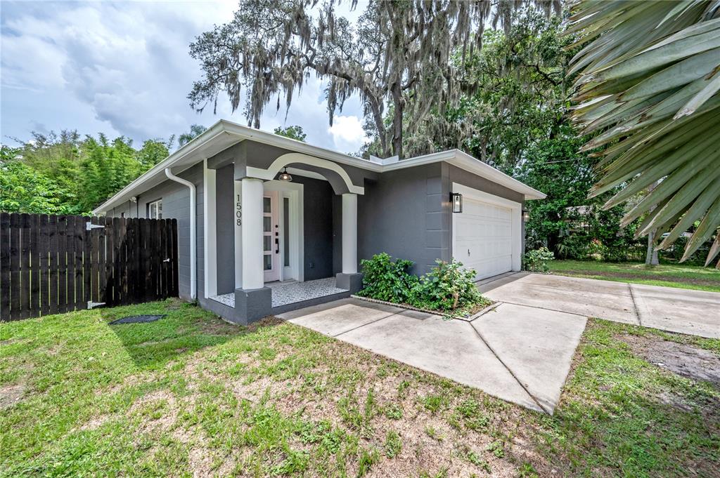 A single-story gray house with a white garage door and a covered front entryway — 1508 E JEAN STREET, TAMPA, FL