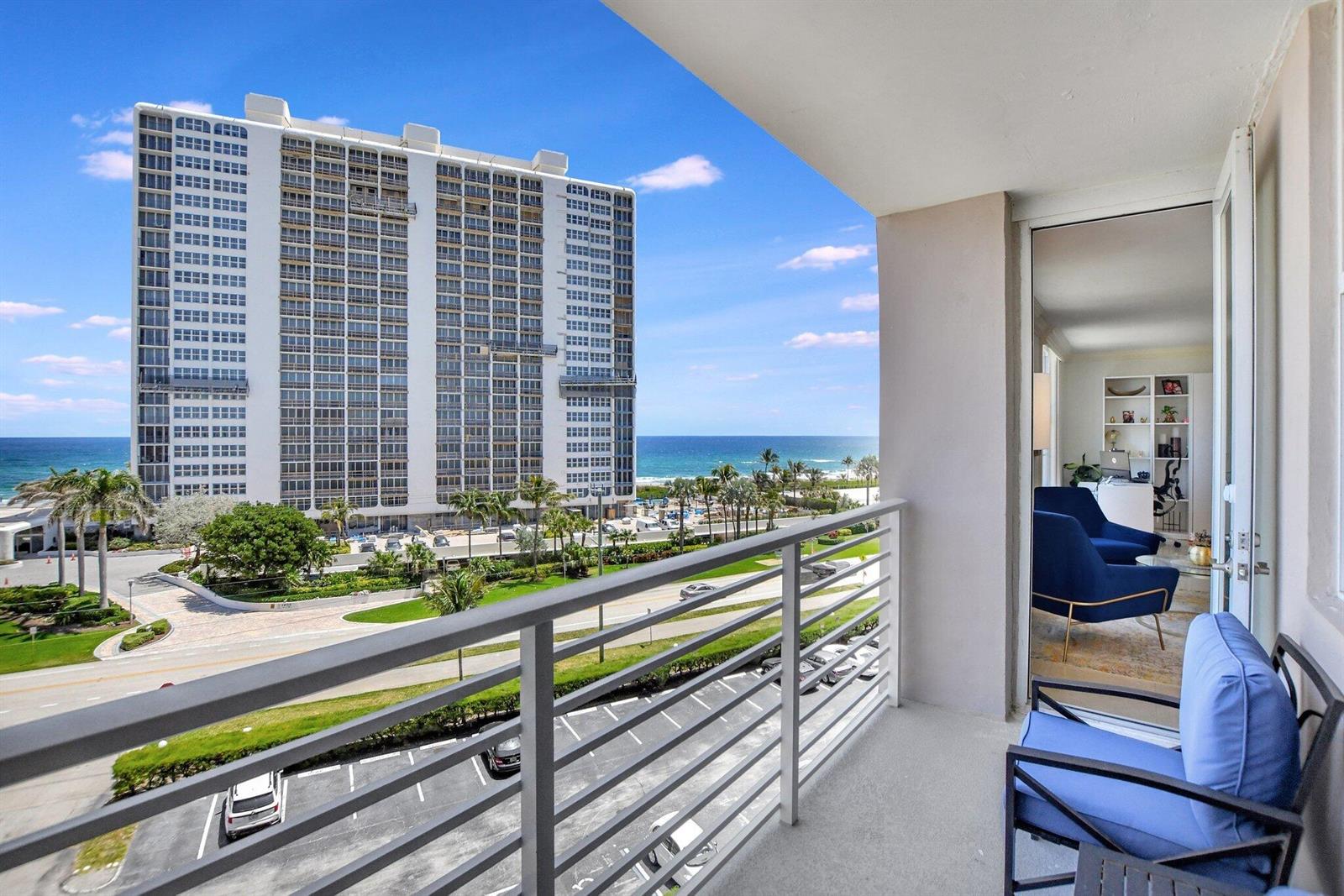A balcony with blue seating overlooks a parking lot, a road, and a tall building — 2851 S Ocean Boulevard # 6n, Boca Raton FL 33432, BOCA RATON, FL