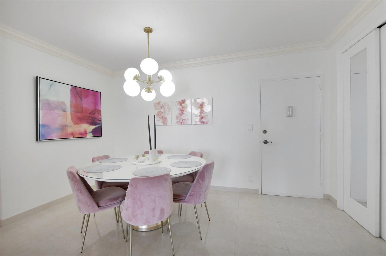 A dining room features a round white table, pink velvet chairs, and a modern chandelier — 2851 S Ocean Boulevard # 6n, Boca Raton FL 33432, BOCA RATON, FL