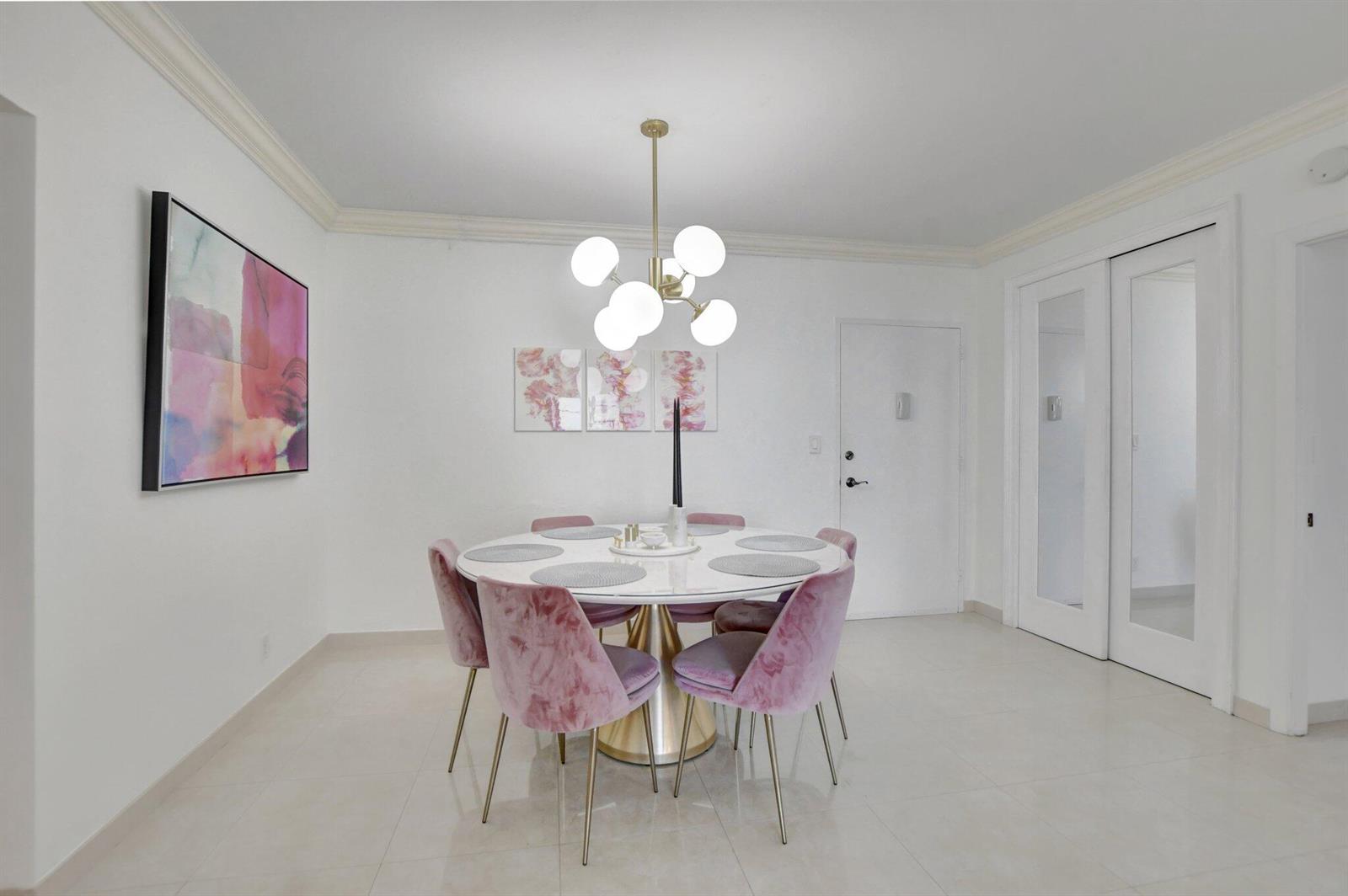A dining room features a round white table, six pink velvet chairs, and a modern chandelier — 2851 S Ocean Boulevard # 6n, Boca Raton FL 33432, BOCA RATON, FL