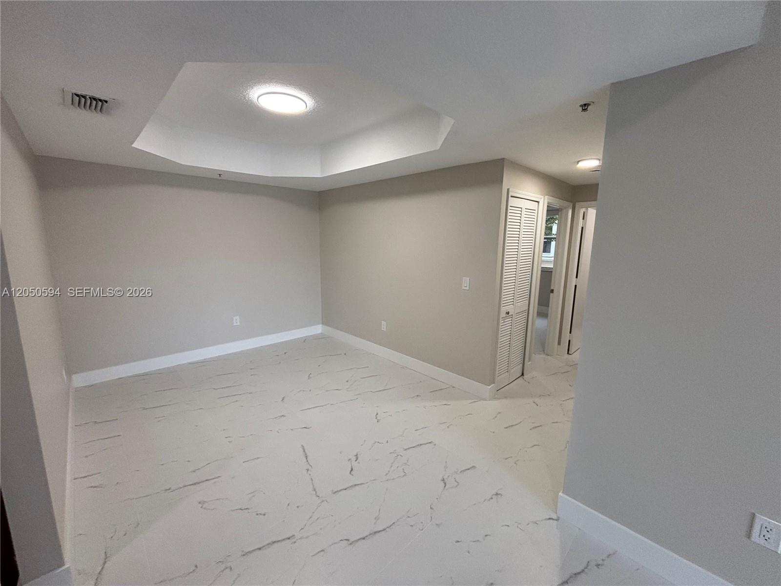 An empty room features a tray ceiling, recessed lighting, and white marble-patterned tile flooring — 6440 NW 114th Ave # 424, Doral FL 33178, DORAL, FL
