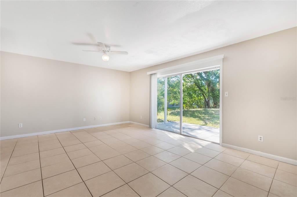 An empty room with beige tile flooring, a ceiling fan, and sliding glass patio doors — 3071 GEORGE MASON AVENUE UNIT 5, WINTER PARK, FL