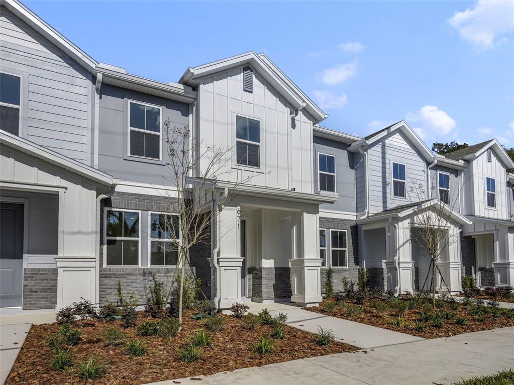 A row of modern townhouses features gray siding, white vertical accents, and brick lower facades — 671 CLARK STREET, OVIEDO, FL