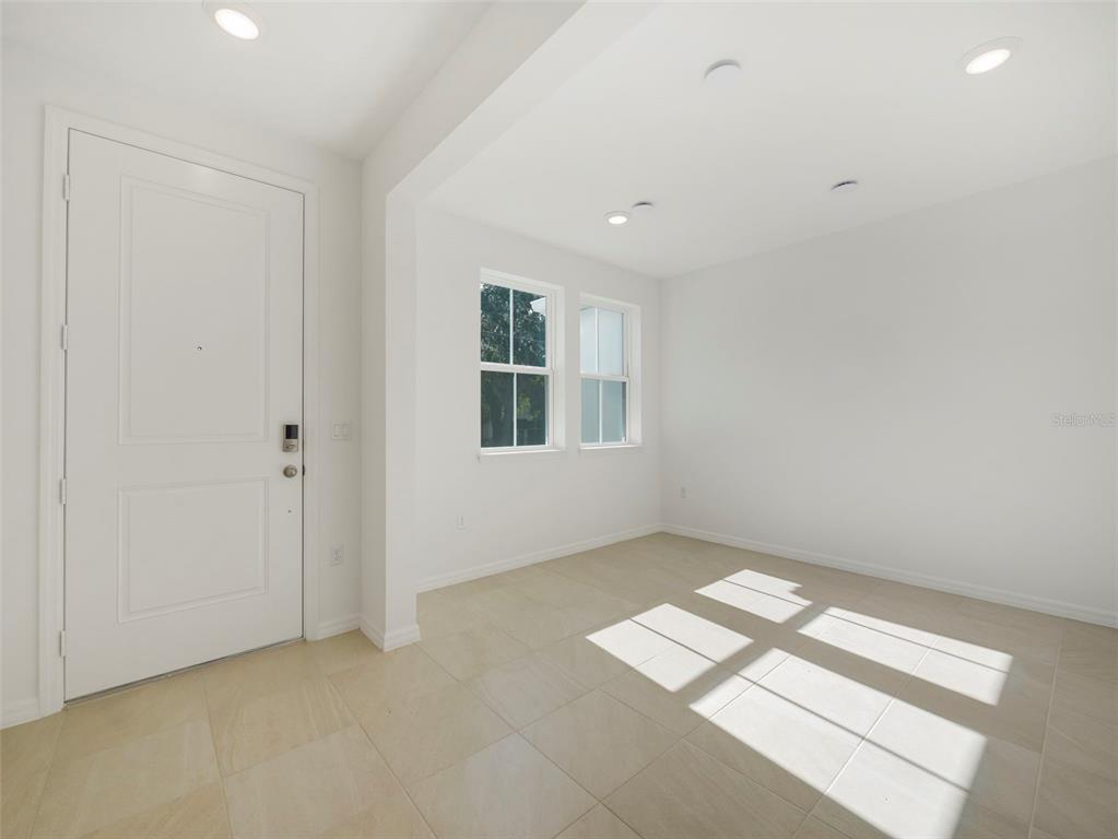 An empty room with white walls, tile flooring, recessed lighting, and a white entry door — 671 CLARK STREET, OVIEDO, FL