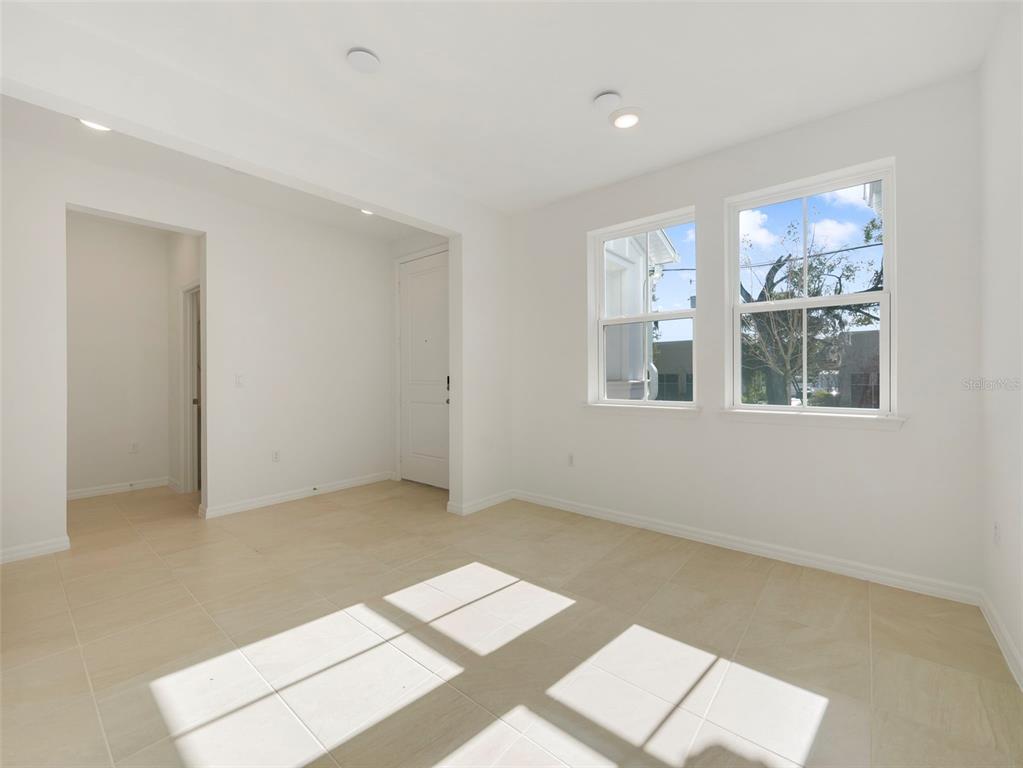 A bright, empty room with white walls, tile flooring, and two windows — 671 CLARK STREET, OVIEDO, FL