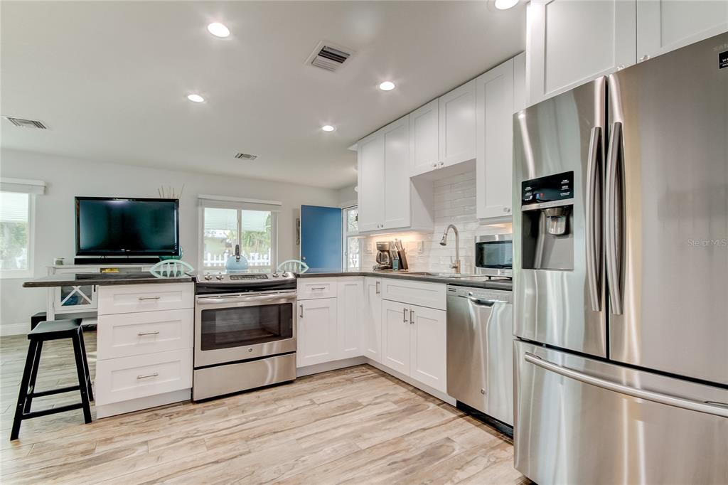 A kitchen with white cabinets, stainless steel appliances, and wood-look flooring — 1907 2ND STREET, INDIAN ROCKS BEACH, FL