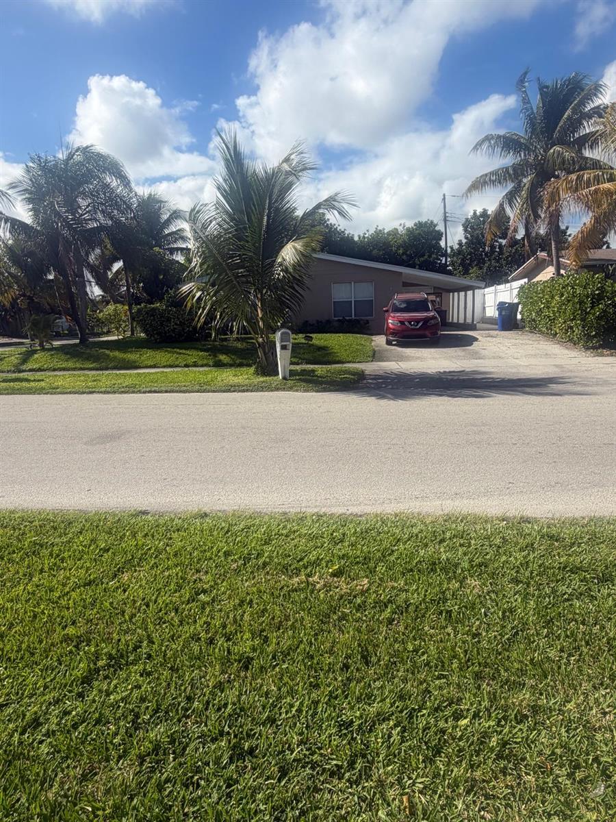 A single-story house with a red car parked in the driveway and palm trees — 2001 NE 2nd Terrace, Pompano Beach FL 33060, POMPANO BEACH, FL