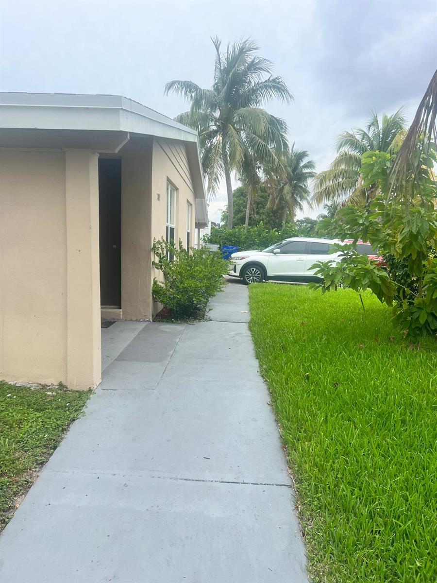 A concrete walkway leads along the side of a beige house toward a parked car — 2001 NE 2nd Terrace, Pompano Beach FL 33060, POMPANO BEACH, FL