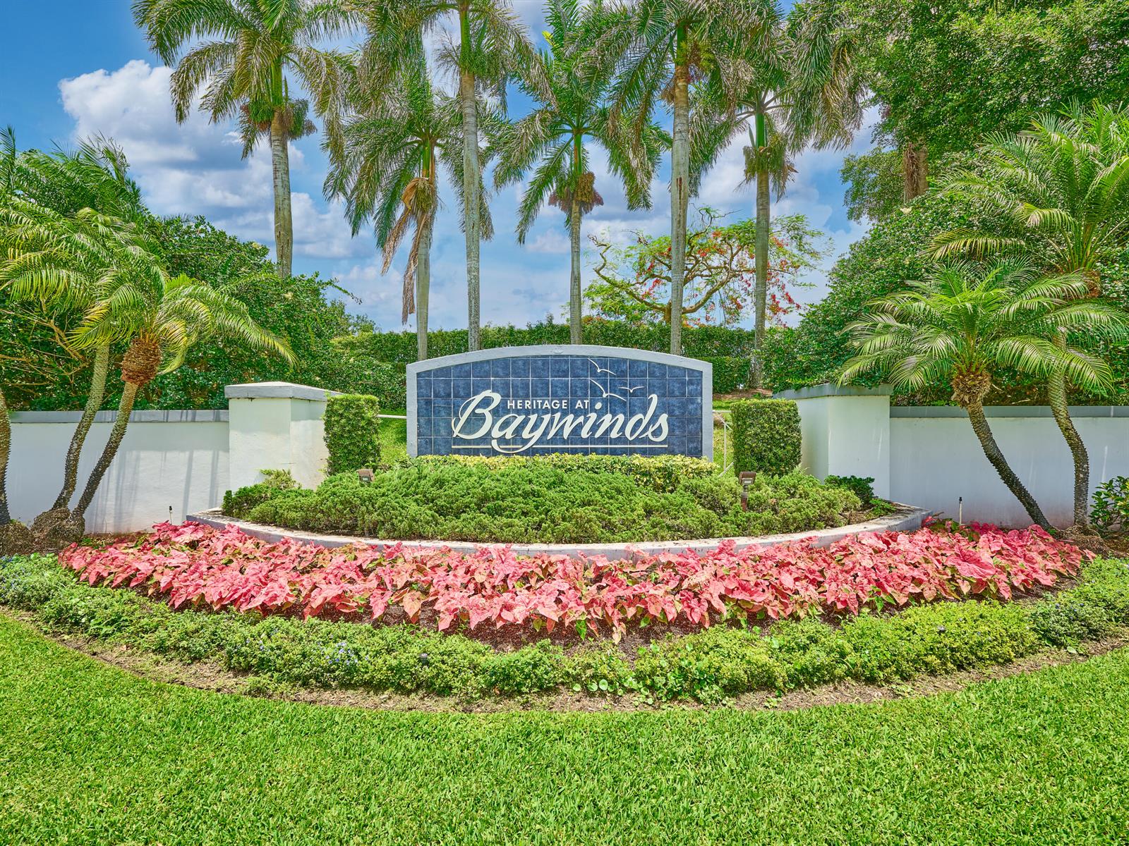 A stone monument sign for Heritage at Baywinds sits amidst landscaping, palm trees, and flowers — 2649 Clipper Circle, West Palm Beach FL 33411, WEST PALM BEACH, FL