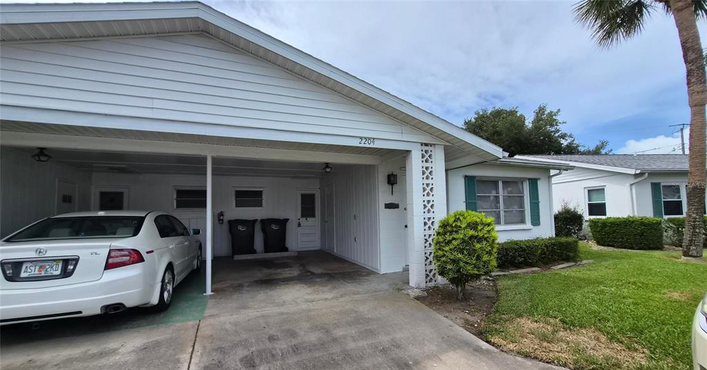 A white house features a carport with a parked car and a small front lawn — 2204 ORANGE BLOSSOM LANE, BRADENTON, FL