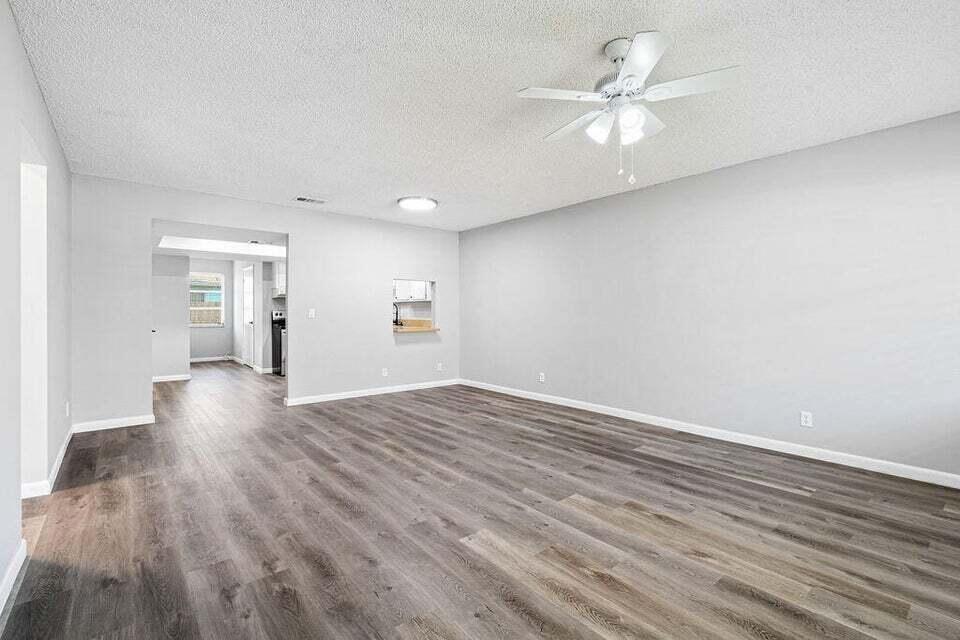 A spacious living room features light gray walls, wood-look flooring, and a ceiling fan — 9046 E Highland Pines Boulevard E, Palm Beach Gardens FL 33418, PALM BEACH GARDENS, FL
