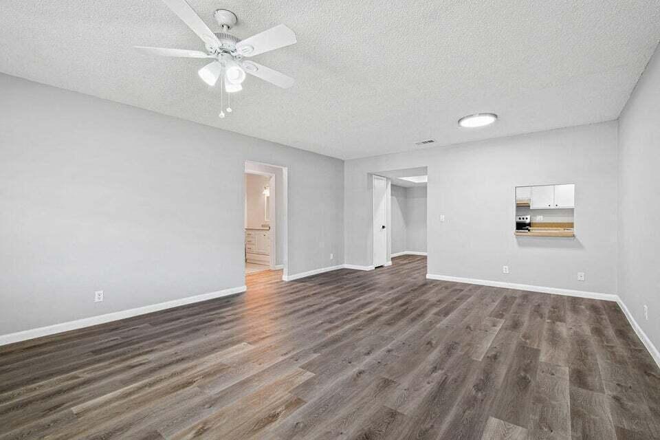 An empty living room features light gray walls, wood-look flooring, and a ceiling fan — 9046 E Highland Pines Boulevard E, Palm Beach Gardens FL 33418, PALM BEACH GARDENS, FL