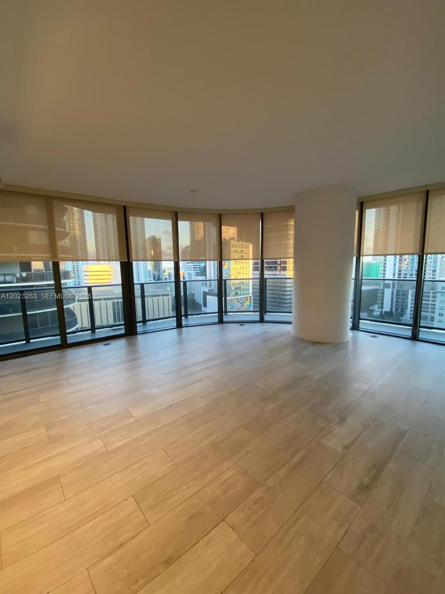 An empty room features light wood-look flooring, a large structural column, and floor-to-ceiling windows — 55 SW 9th St # 1503, Miami FL 33130, MIAMI, FL