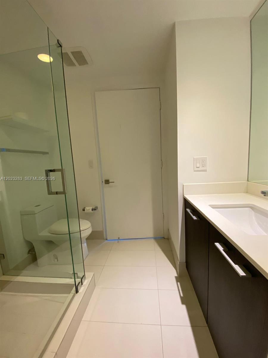 A bathroom features a glass-enclosed shower, a white toilet, and a dark wood vanity — 55 SW 9th St # 1503, Miami FL 33130, MIAMI, FL