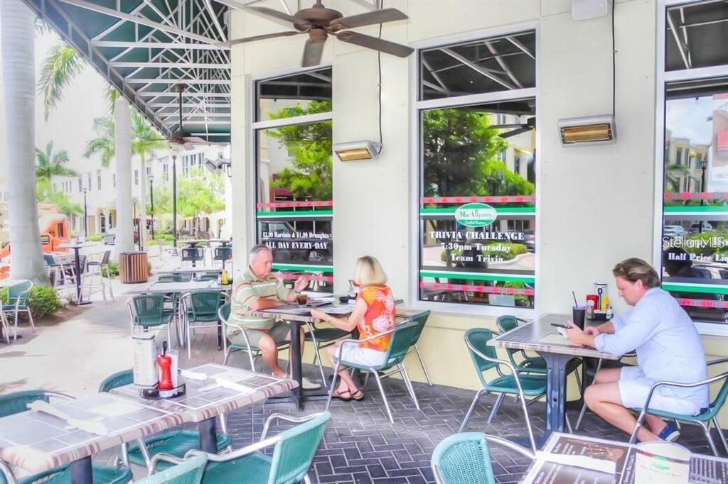 An outdoor patio dining area features tables, chairs, and signage for a restaurant — 8111 LAKEWOOD MAIN STREET UNIT 307, LAKEWOOD RANCH, FL