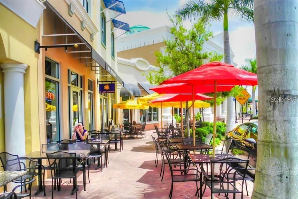 Outdoor patio seating area with tables, chairs, and umbrellas outside a commercial building — 8111 LAKEWOOD MAIN STREET UNIT 307, LAKEWOOD RANCH, FL