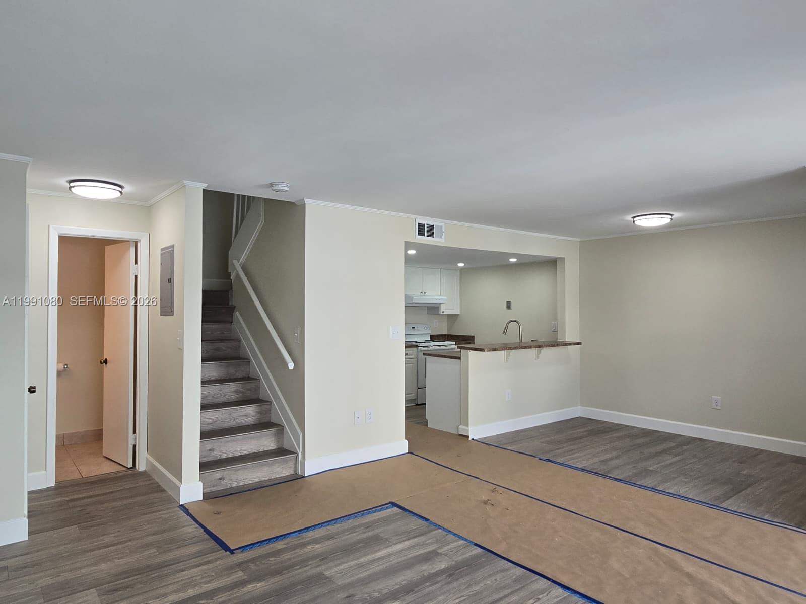 An interior view shows a living area with stairs, a kitchen pass-through, and wood-look flooring — 6825 SW 45th Ln # 12, Miami FL 33155, MIAMI, FL