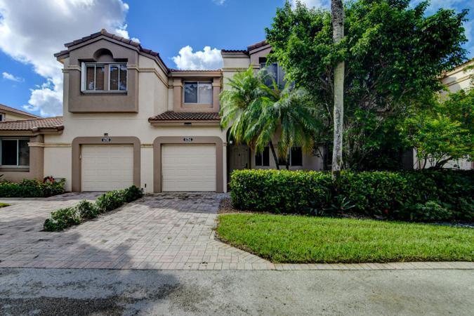 A two-story tan stucco townhouse features a paver driveway, two garage doors, and lush landscaping — 6784 Via Regina, Boca Raton FL 33433, BOCA RATON, FL