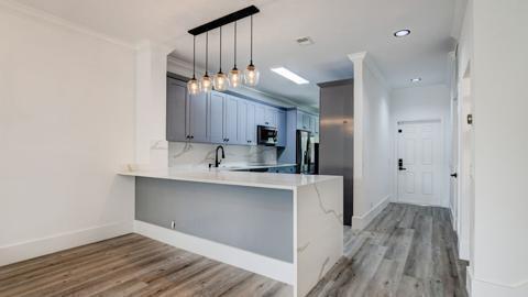 A modern kitchen features light blue cabinets, a white quartz island, and wood-look flooring — 6784 Via Regina, Boca Raton FL 33433, BOCA RATON, FL