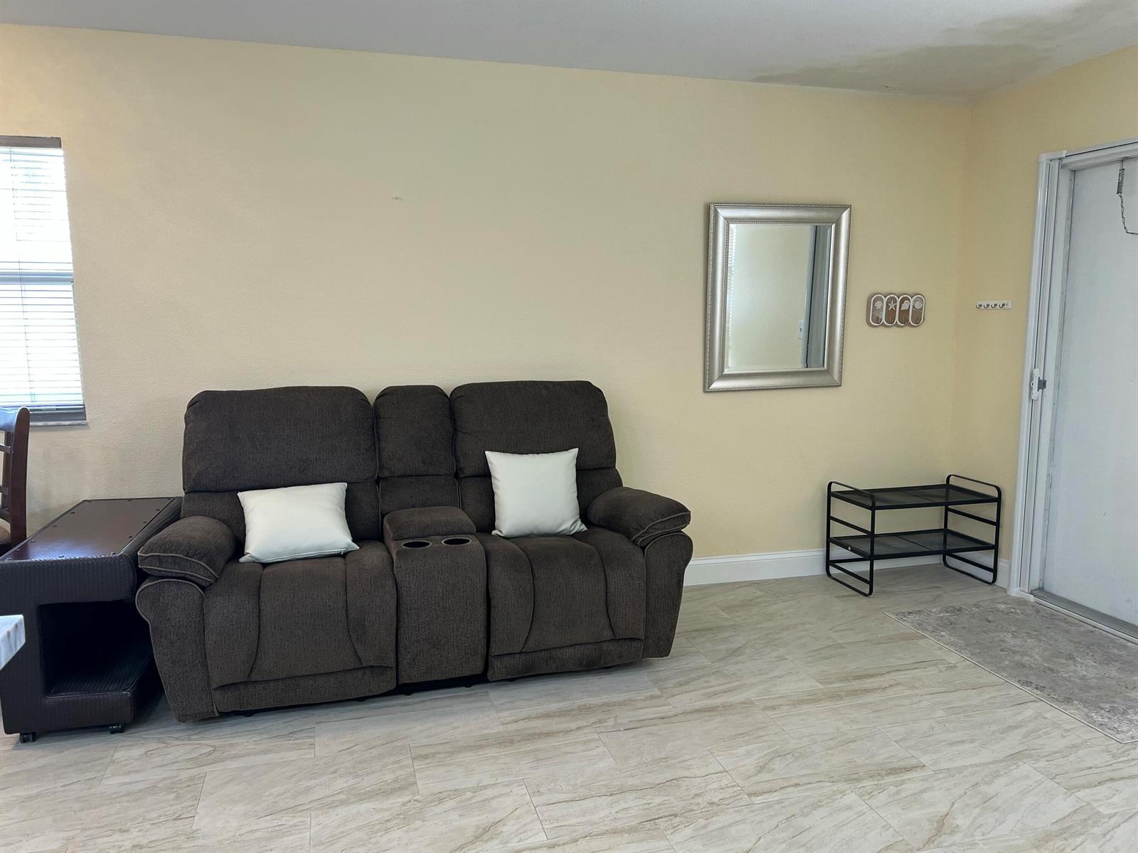 A living room features a brown reclining loveseat, a mirror, and a shoe rack — 711 Monaco Court, Delray Beach FL 33446, DELRAY BEACH, FL