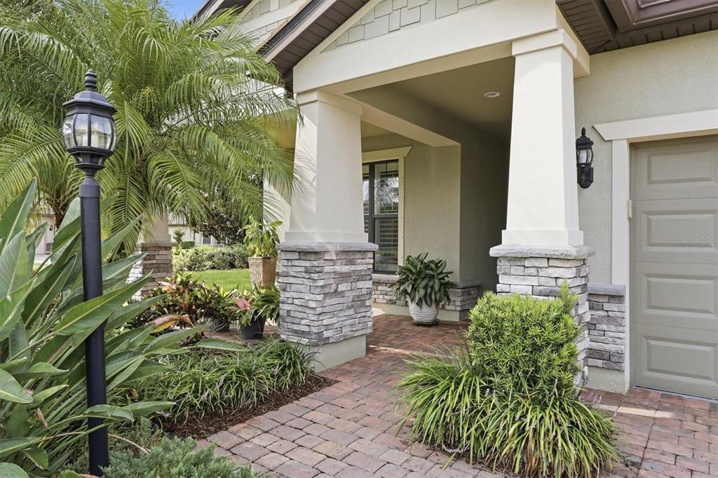A paved walkway leads to a covered front porch with stone-based columns and landscaping — 16932 PELHAM PLACE, LAKEWOOD RANCH, FL