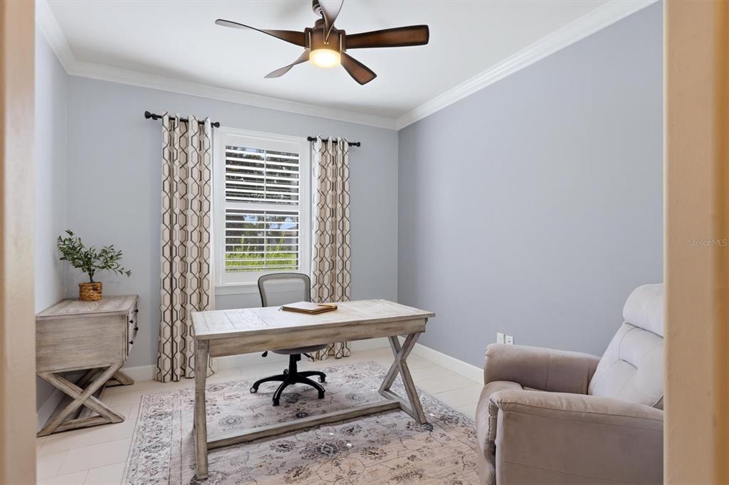 A home office features a wooden desk, an armchair, a ceiling fan, and a window — 16932 PELHAM PLACE, LAKEWOOD RANCH, FL