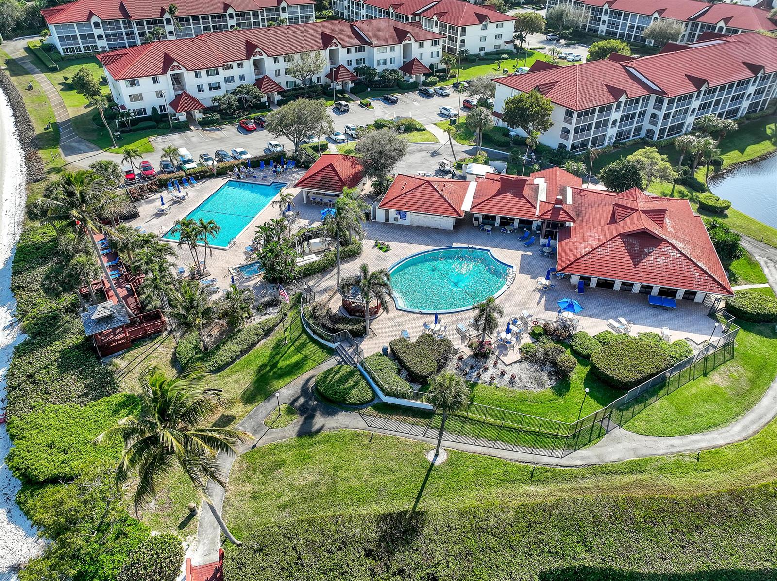 An aerial view of a residential complex featuring two swimming pools and red-roofed buildings — 105 Half Moon Circle # F1, Hypoluxo FL 33462, HYPOLUXO, FL