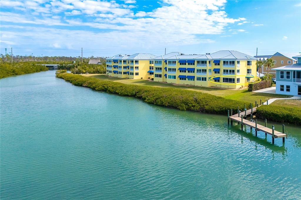 An aerial view shows a yellow multi-story waterfront condominium building with a circled ground-floor unit — 2424 PLACIDA ROAD UNIT C101, ENGLEWOOD, FL