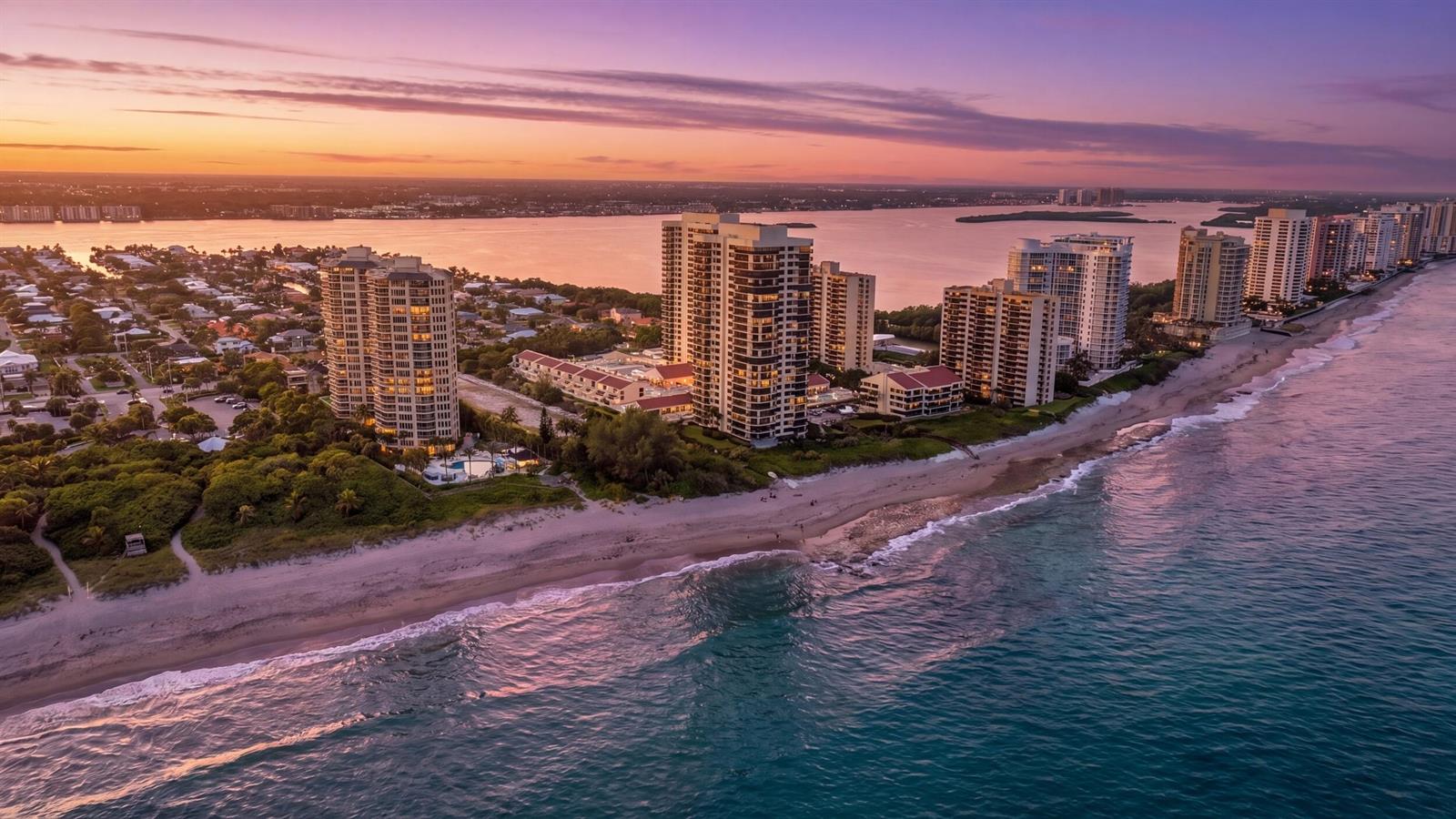 An aerial view of high-rise condominiums situated along a sandy beach at sunset — 4200 N Ocean Drive # 405, Singer Island FL 33404, SINGER ISLAND, FL