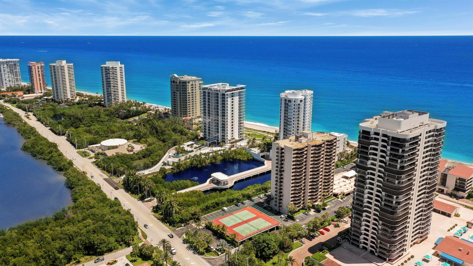 Aerial view of high-rise residential buildings along a coastline with a tennis court and lake — 4200 N Ocean Drive # 405, Singer Island FL 33404, SINGER ISLAND, FL