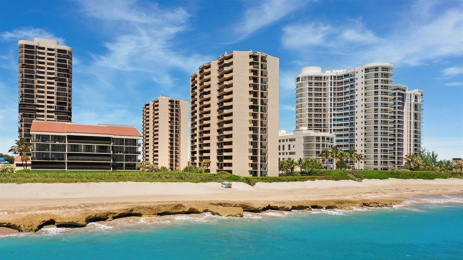 High-rise residential buildings stand along a sandy beach with a rocky shoreline — 4200 N Ocean Drive # 405, Singer Island FL 33404, SINGER ISLAND, FL