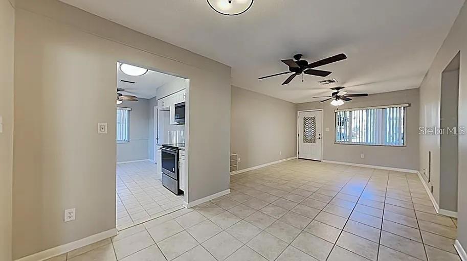 A tiled living area opens into a kitchen with white cabinets and stainless steel appliances — 7481 OAK STREET NE, ST PETERSBURG, FL