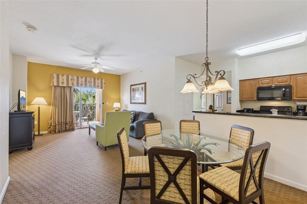 A living and dining area with carpeted floors, a glass table, and an open kitchen — 8112 POINCIANA BOULEVARD UNIT 1202, ORLANDO, FL